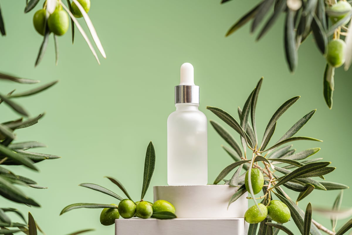 Colorful green leaves with skincare facial oil serum bottle